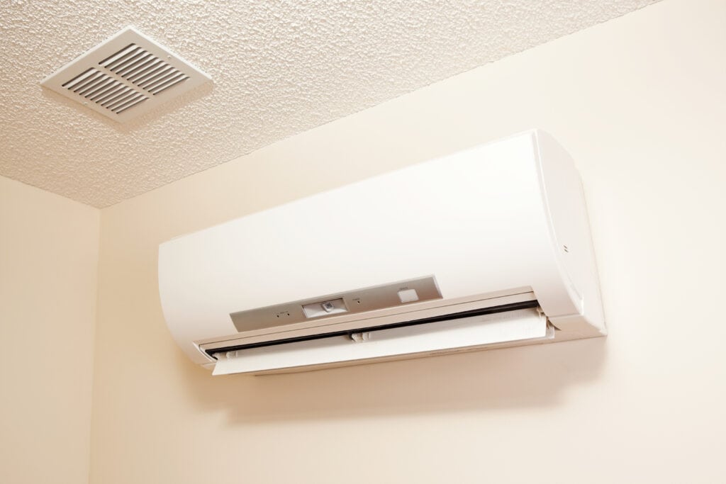 A wall-mount mini-split heating and air conditioning unit installed in a new house. A modern heat pump, this unit heats a house in winter and cools in the summer. This type of system eliminates ductwork which is a primary source of inefficiency in a conventional system making this about 30% more efficient. This particular unit has an eye sensor which pans the room looking for hot or cold spots and directs the airflow accordingly.