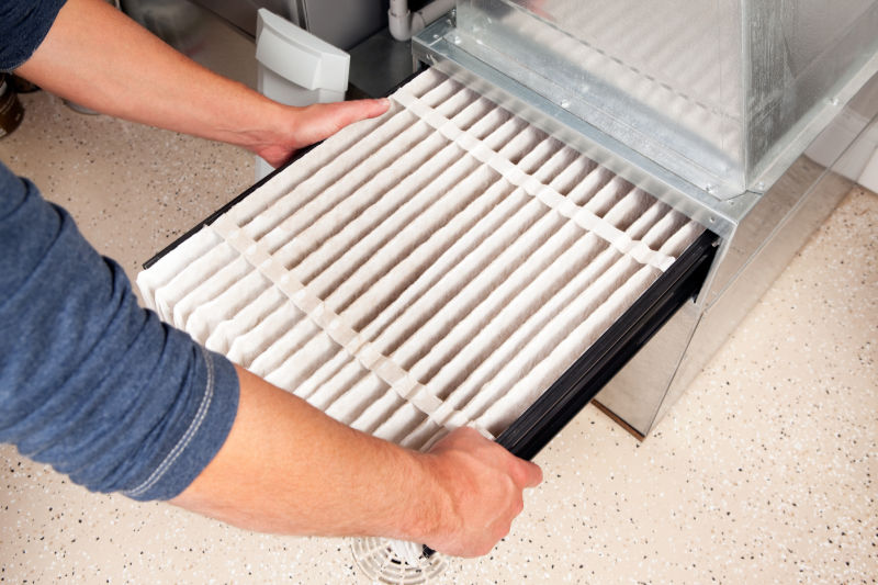 Why Is Changing Your Furnace Filter Important? Pair of hands changing out a furnace filter.