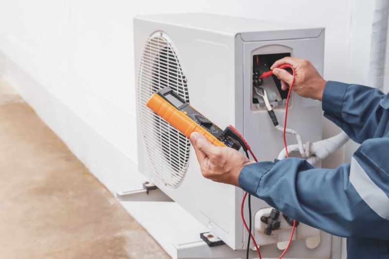 Image of someone working on AC unit. When and Why to Schedule an AC Tune-Up.