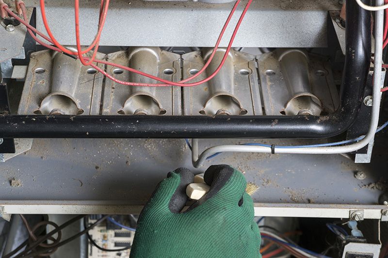 Image of someone working on a furnace. 5 reasons to schedule a fall furnace clean and check.