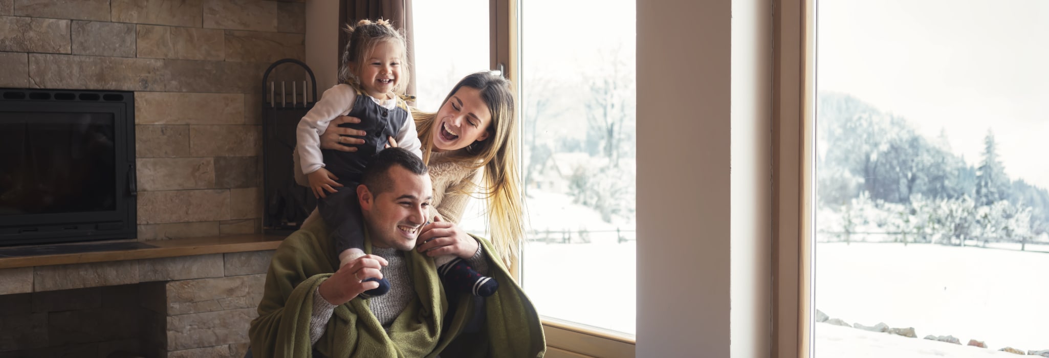 Young family on winter vacation, looking through window.