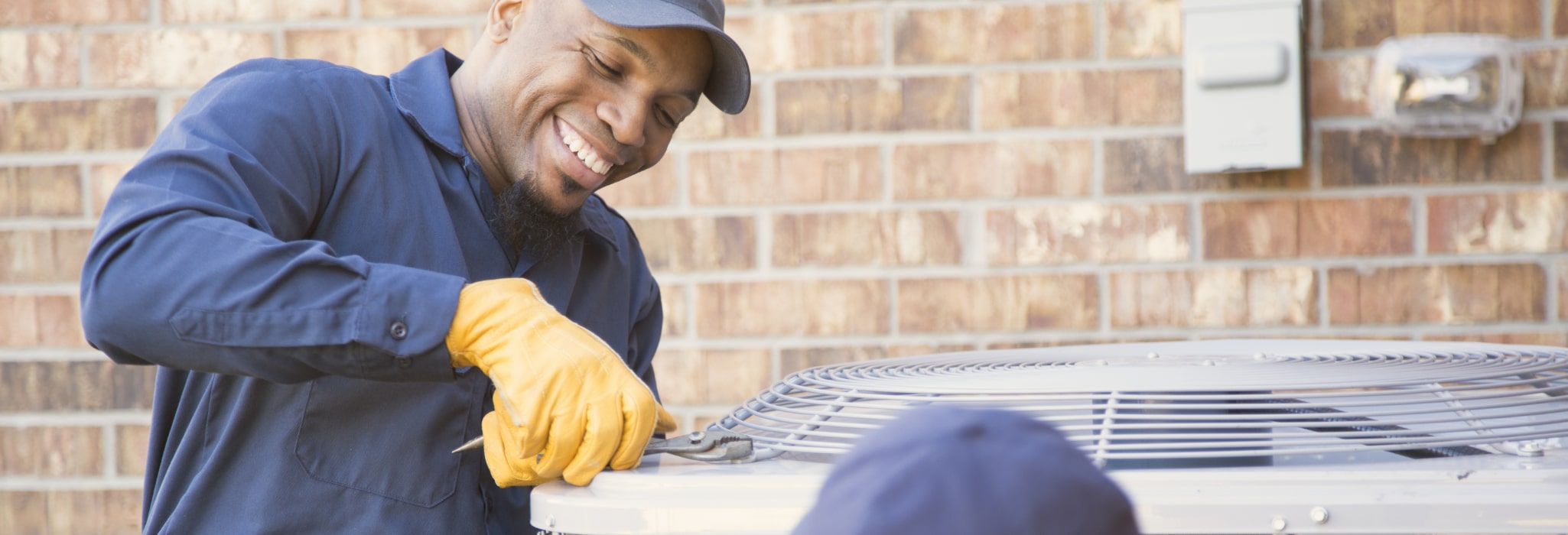 Multi-ethnic team of blue collar air conditioner repairmen at work.  They prepare to begin work by gathering appropriate tools from their tool box.